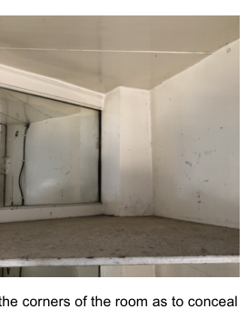 A close-up photograph of an interior room corner showing a window and white walls.