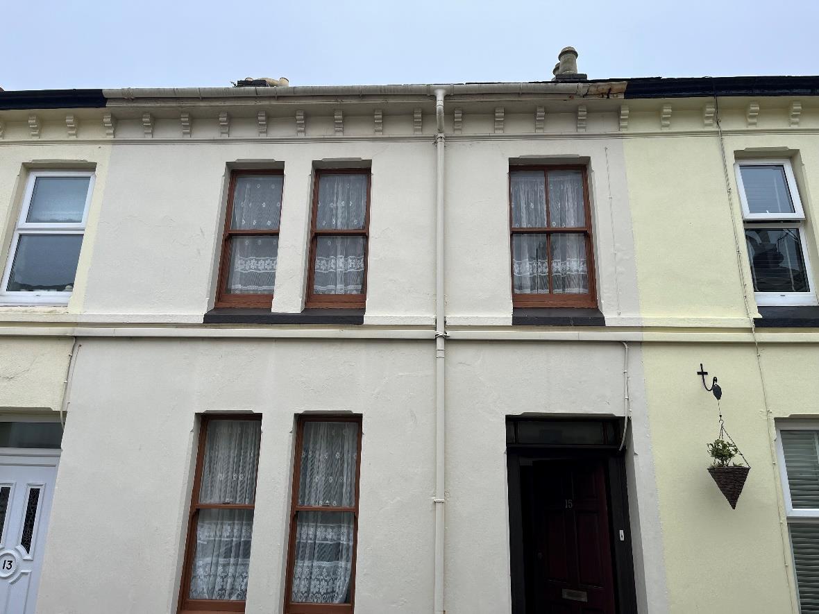 A photograph showing the front elevation of a two-story terraced house with cream rendering and traditional wooden sash windows.