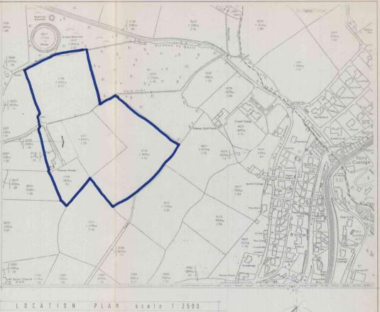 A black and white location plan map showing a site outlined in blue, with surrounding fields and a settlement visible to the right.