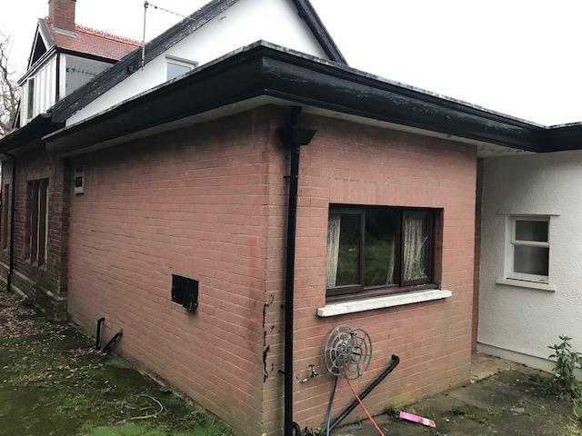 Exterior photograph of an existing residential property showing a red brick wall section next to a white rendered wall.