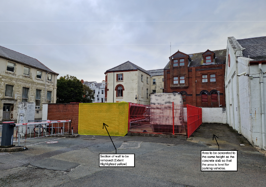 A photograph of a paved site area showing temporary fencing and buildings, with annotations indicating a wall section to be removed and an area to be concreted for parking.