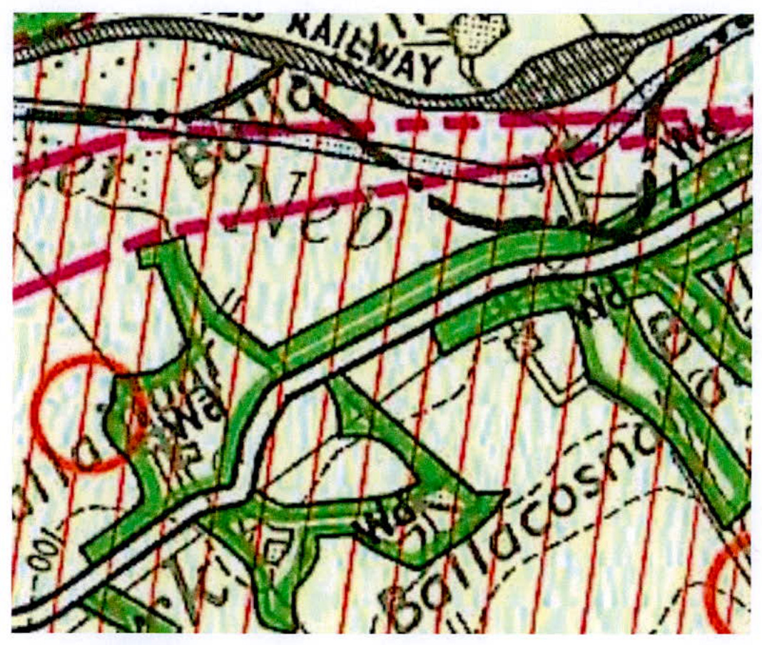 A close-up section of a topographical map showing green fields, a railway line, and red boundary markings.