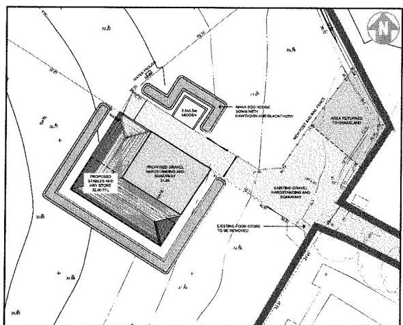 A black and white site plan showing proposed stables, hay store, and hardstanding areas with contour lines and existing structures.