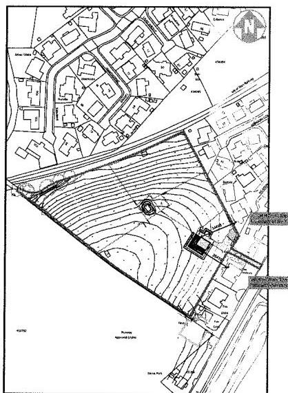 This image displays a black and white site plan featuring contour lines indicating topography, a proposed building footprint, and surrounding property boundaries.