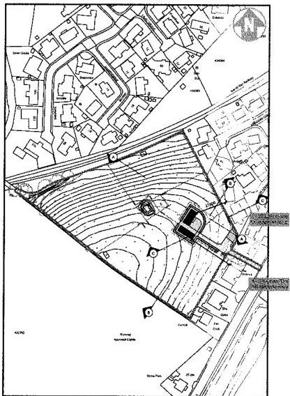 A black and white site plan showing a plot of land with contour lines, surrounded by residential and agricultural buildings.