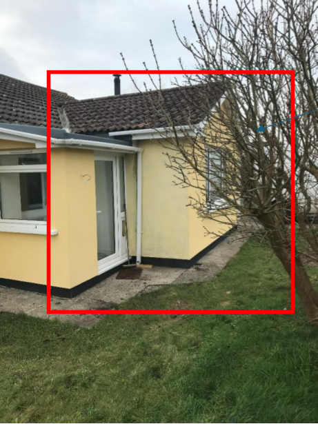 A photograph showing the exterior of a yellow detached house with a red bounding box highlighting an existing single-story conservatory extension.