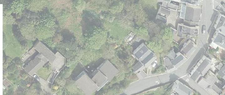 An aerial map view showing a cluster of houses with slate roofs, roads, and surrounding green vegetation.