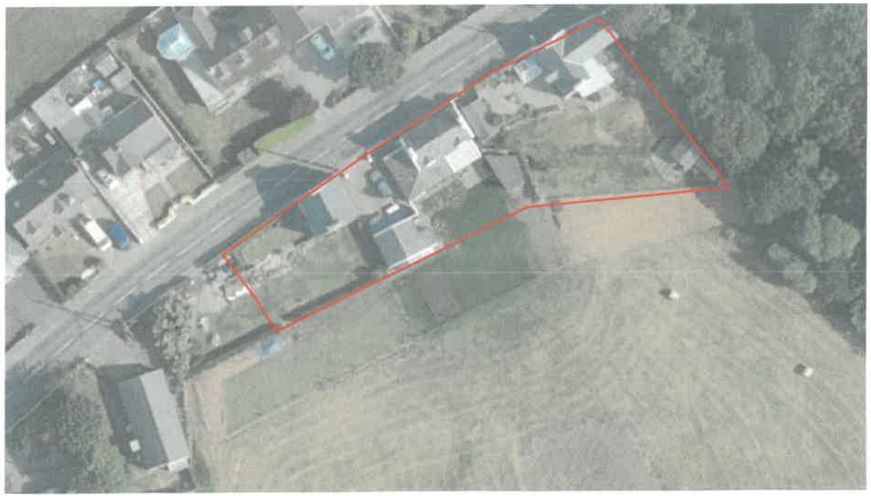 An aerial photograph showing a rural property with a red polygon outlining the site boundary and adjacent field.