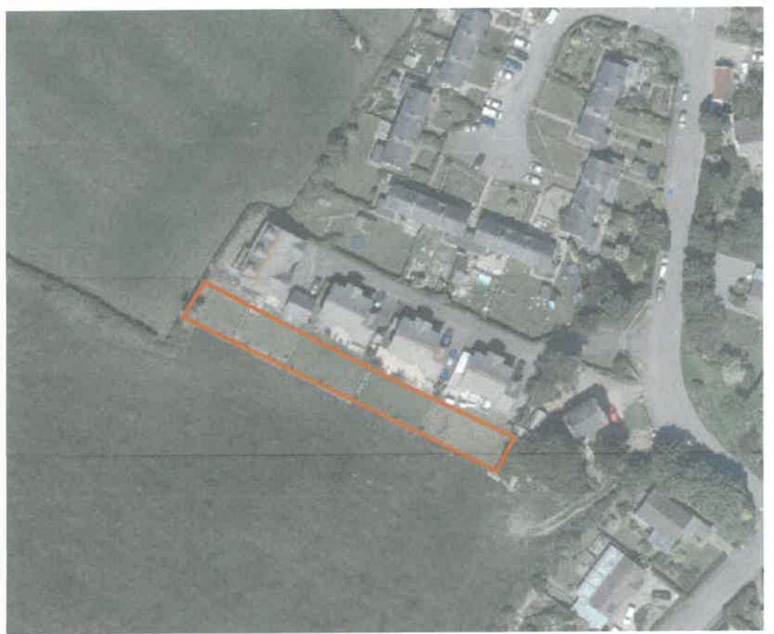 An aerial view showing a row of houses adjacent to a field, with an orange rectangle outlining a specific area of land for curtilage extension.