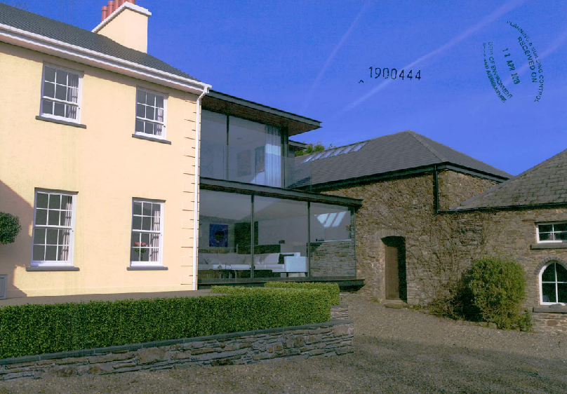 A photograph showing a cream rendered house connected to a stone outbuilding via a modern single-storey glass extension.