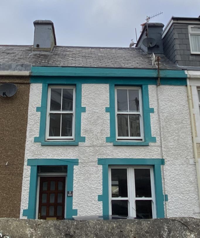 A photograph showing the front elevation of a two-story terraced house with white render and distinctive teal window surrounds.