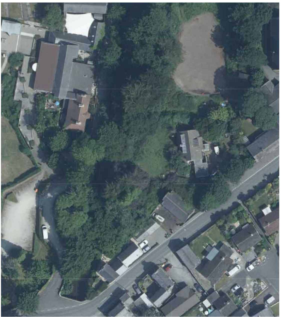 Aerial satellite image showing a rural plot of land surrounded by trees, roads, and existing residential properties.