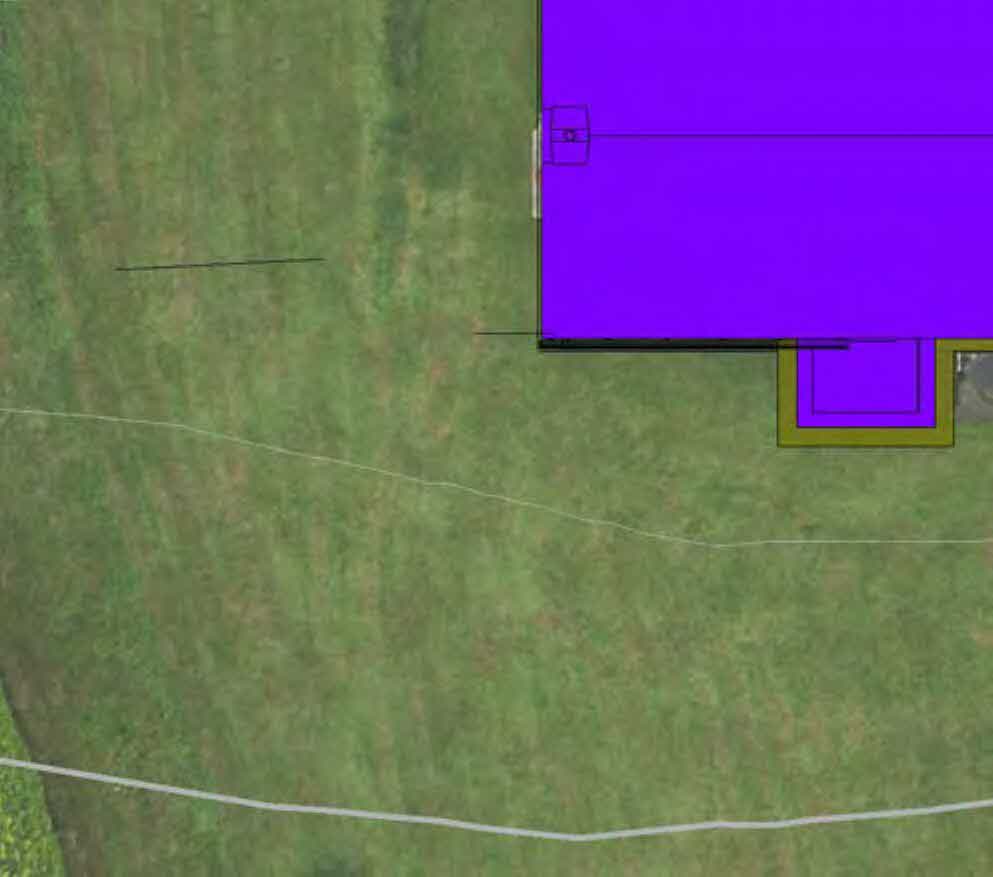Aerial site plan showing proposed building footprints in purple and yellow overlaid on a grassy field.