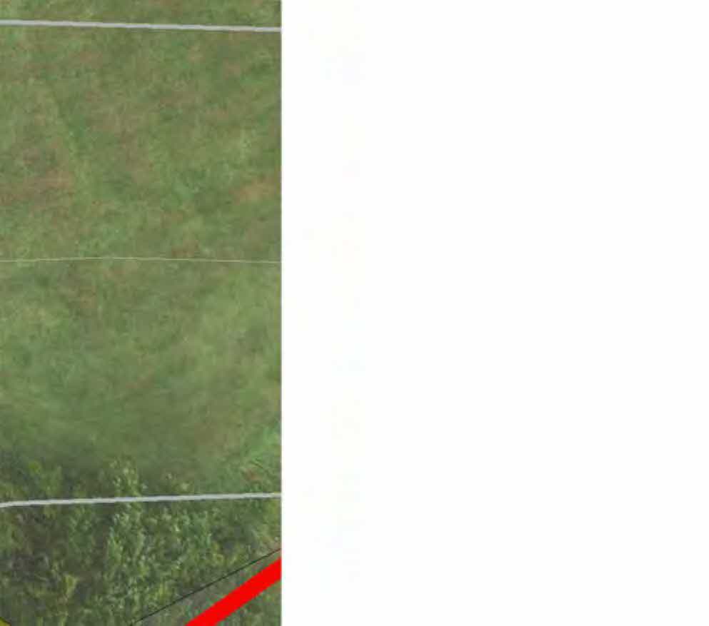 A cropped view of a site plan or aerial map showing a grassy field with white boundary lines and a red highlighted area.