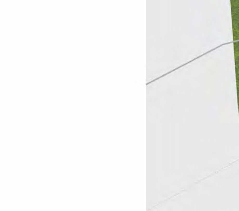 A close-up view of a white exterior wall surface with a faint horizontal line and a small strip of green grass on the right edge.