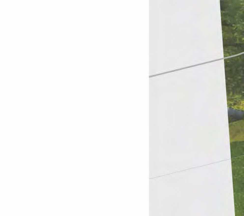 A close-up view of a white vertical wall or panel with horizontal lines, situated next to green vegetation.