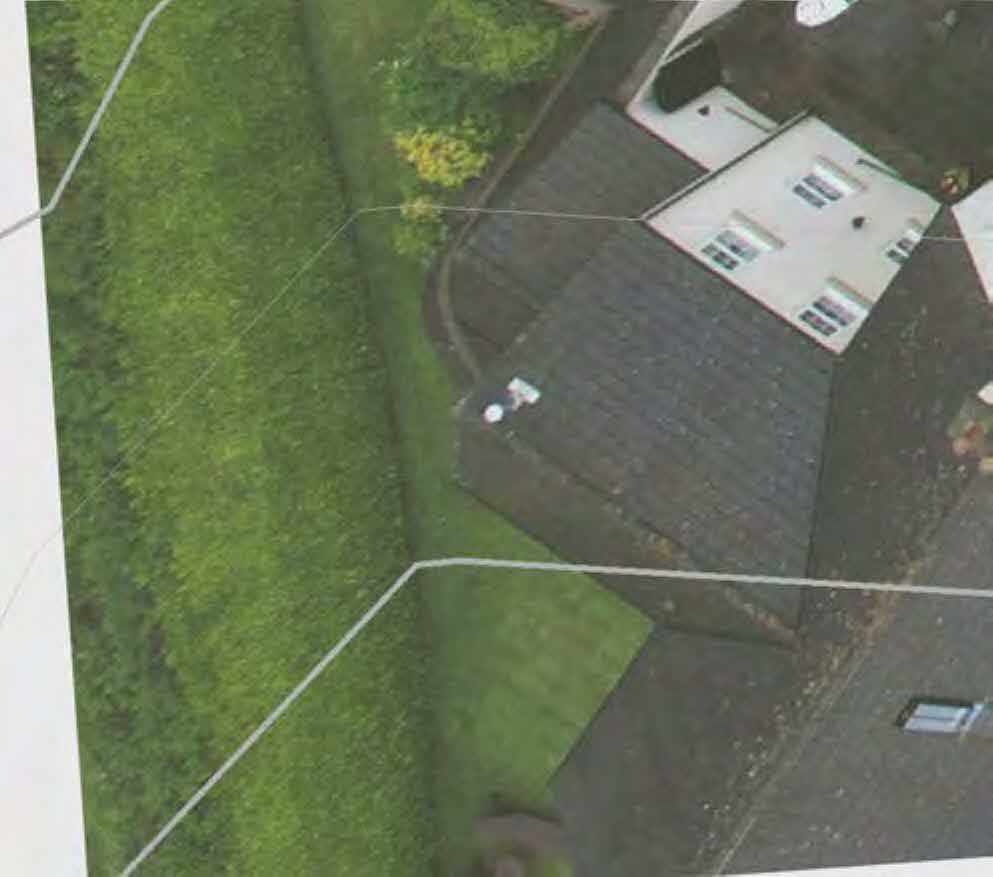 An aerial view of a residential property showing a house roof and garden with white boundary lines overlaid.