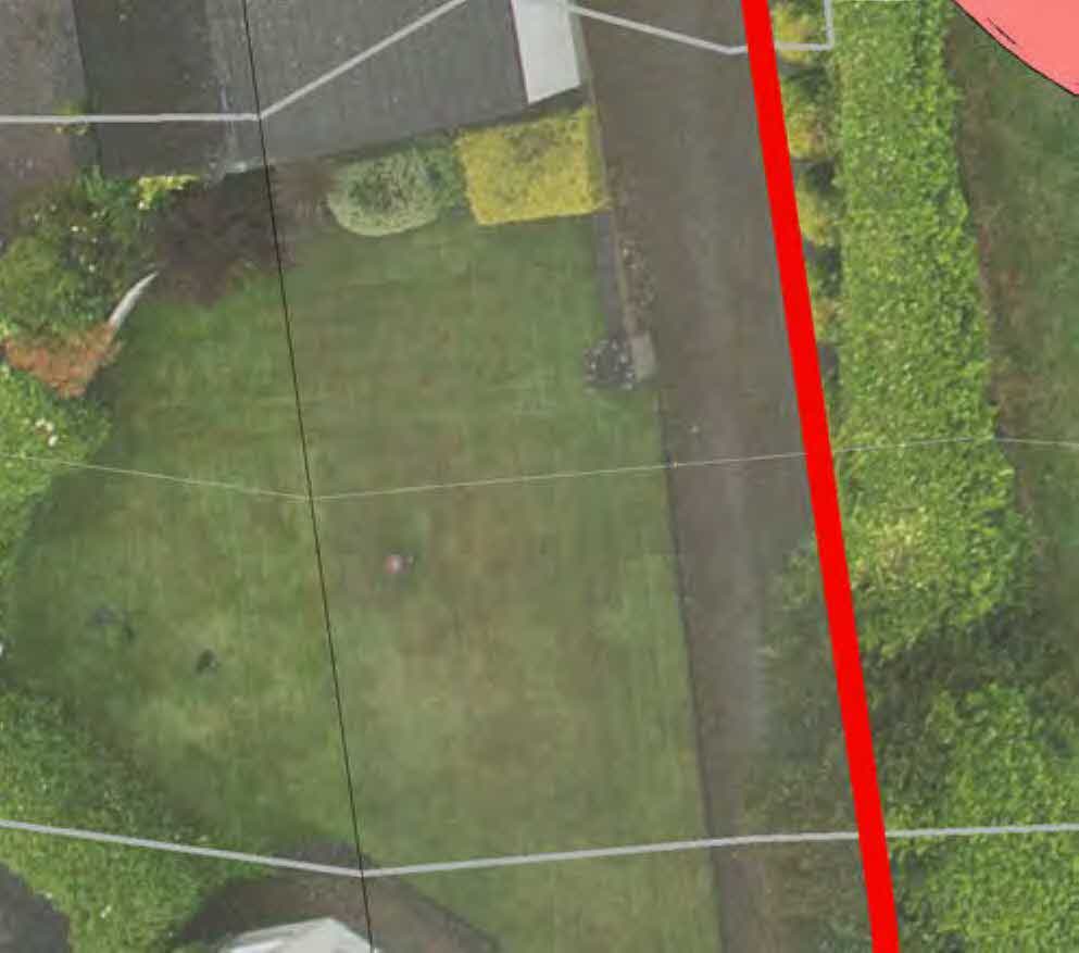 Aerial view of a residential property site plan showing a lawn, driveway, and hedges with overlaid boundary lines.
