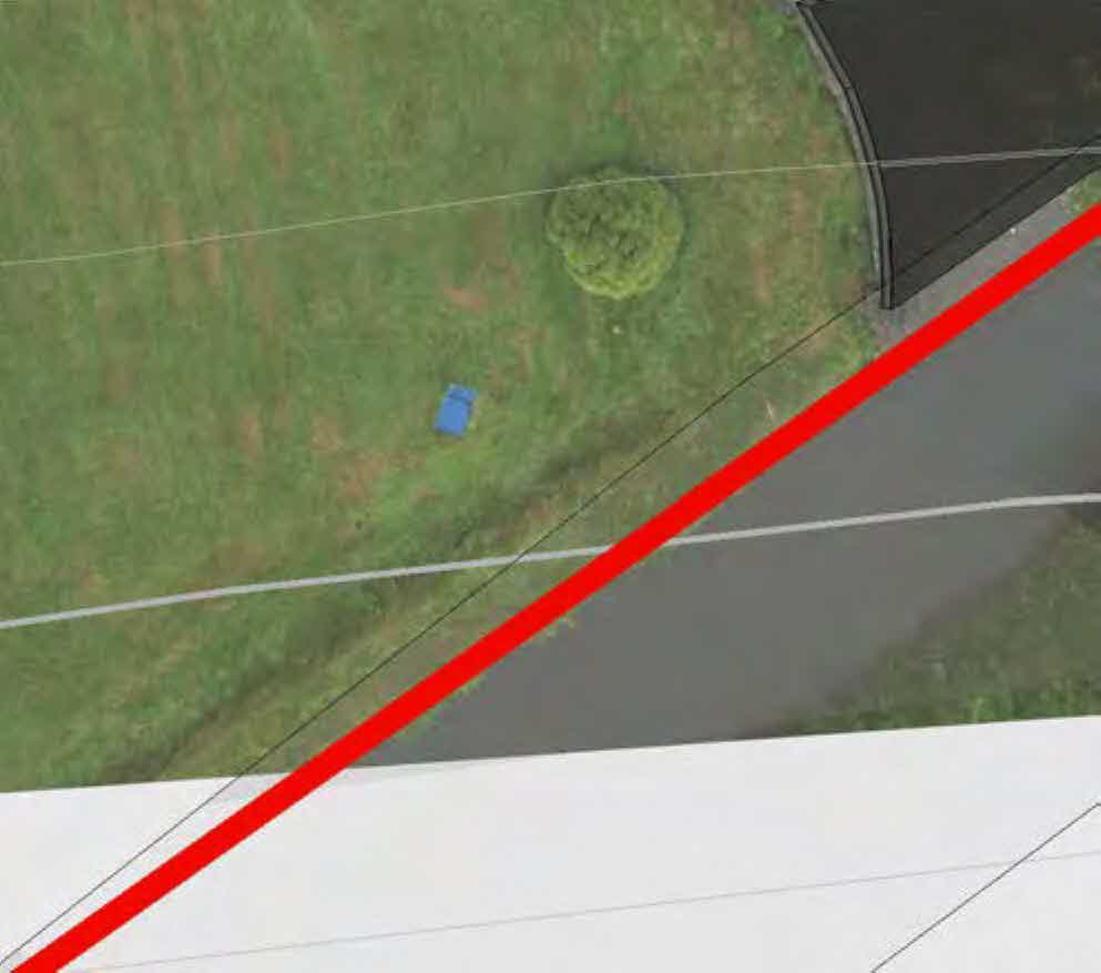 An aerial view of a grassy plot with a road and a prominent red line overlaid, likely indicating a boundary or site limit.