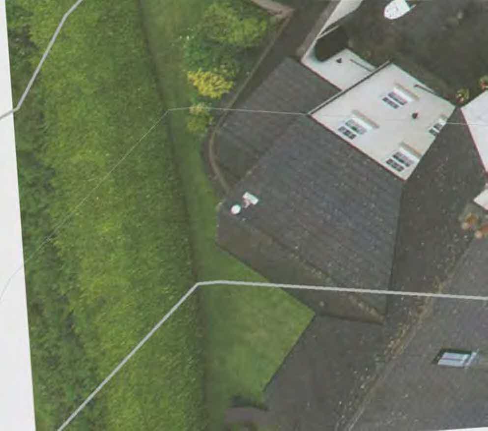 An aerial view of a residential property showing the roof, garden, and surrounding greenery with white boundary lines overlaid.