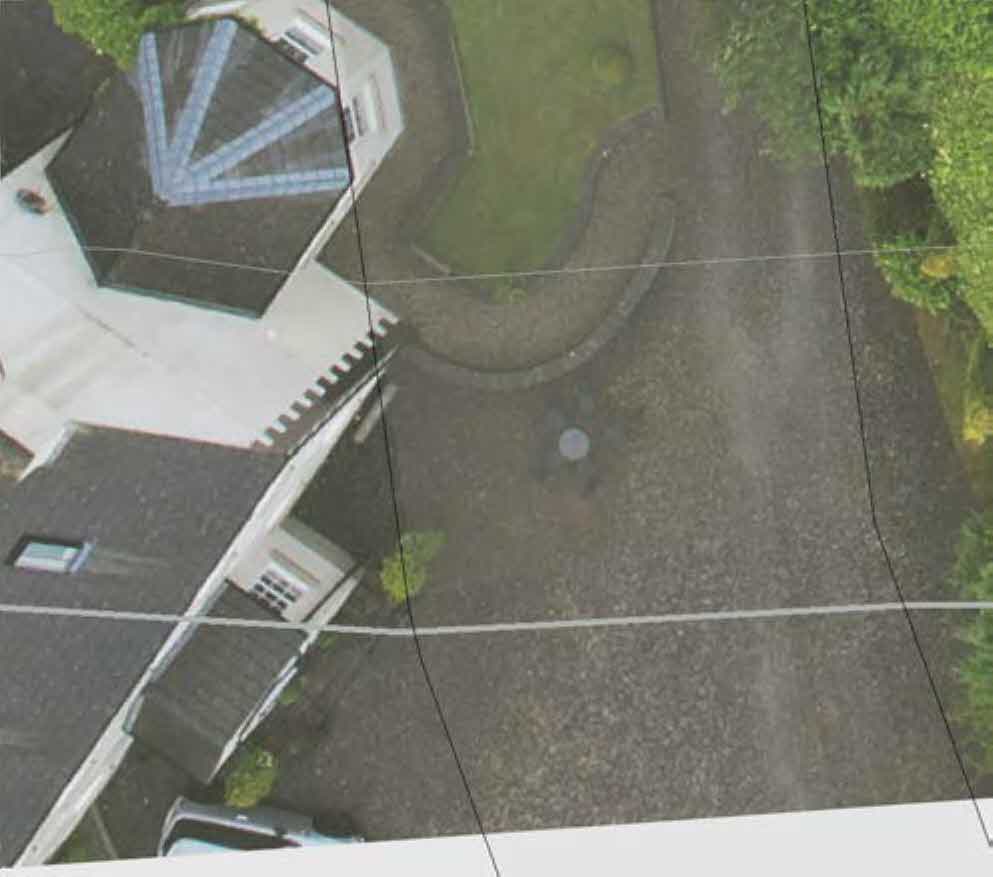 An aerial photograph showing a detached house with a gravel driveway, garden, and surrounding vegetation.