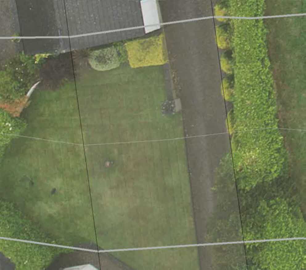 An aerial view of a residential property showing a lawn, driveway, and hedges with white lines indicating boundaries or proposed works.
