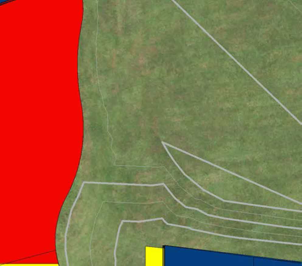 Aerial site plan showing white boundary lines and colored blocks representing buildings on a grassy plot.