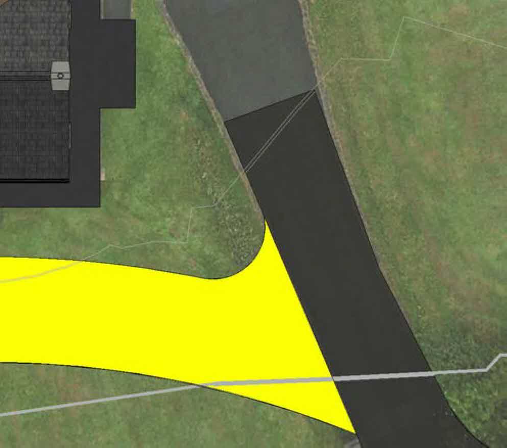 An aerial site plan view showing a property with a building footprint, driveway, and a large yellow highlighted zone on green land.