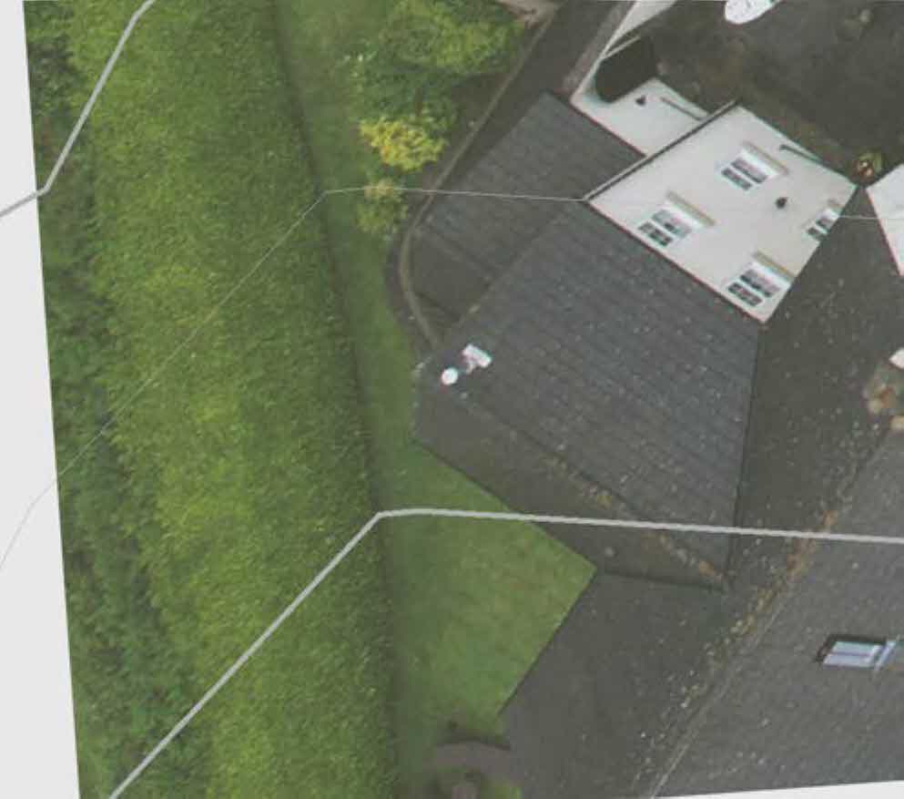 An aerial view of a residential property showing a house with a dark roof and a large green garden, overlaid with white boundary lines.