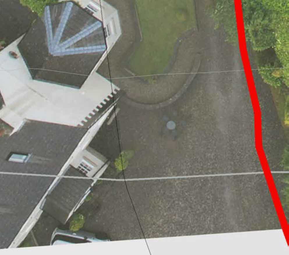 Aerial view of a residential property showing the house, driveway, and garden area with a red boundary line.