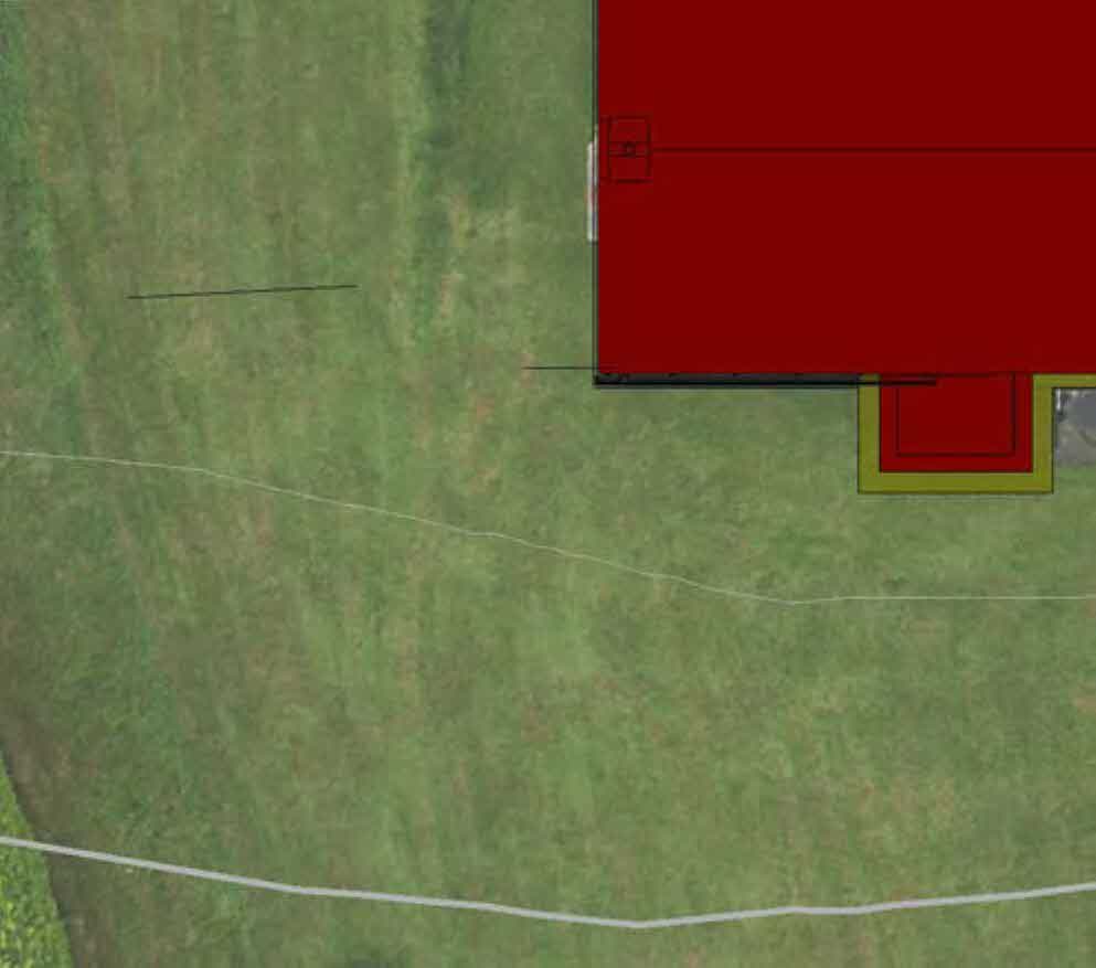 Aerial site plan showing a red building footprint overlaid on a green grassy field with boundary lines.