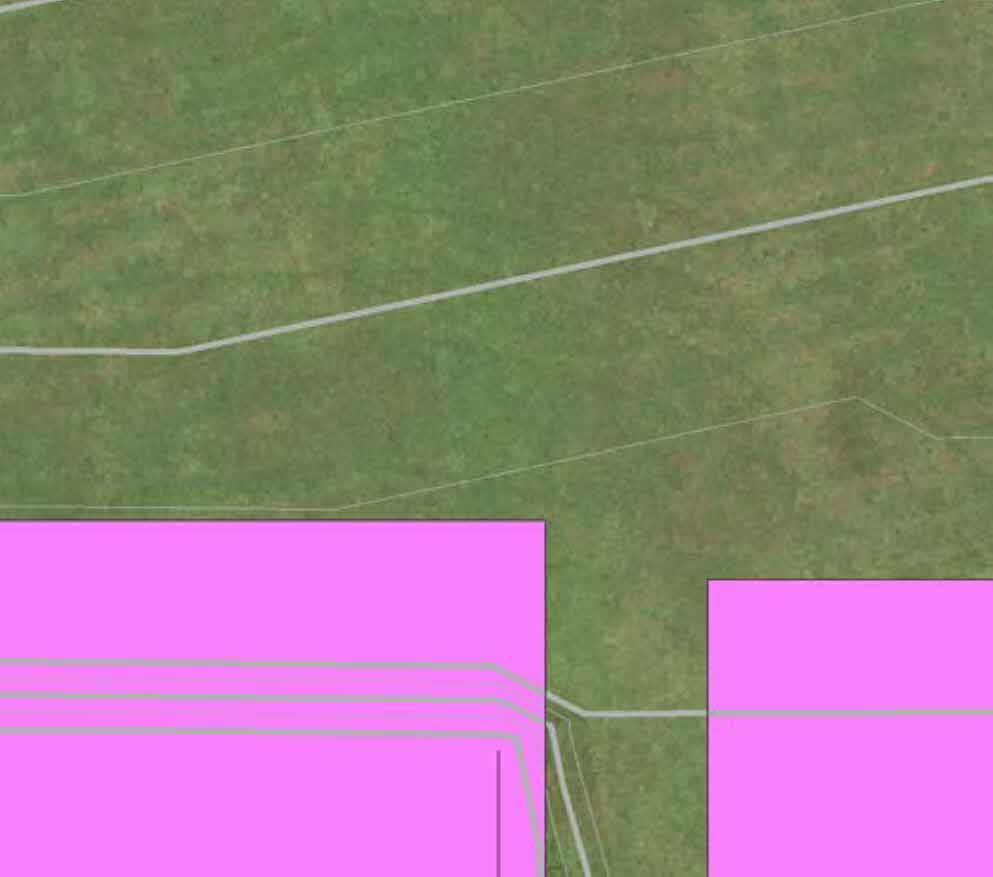 A site plan showing green land with white boundary lines and pink highlighted rectangular areas representing building footprints or land parcels.