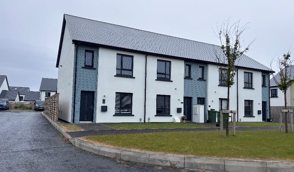 A street-level photograph showing a row of modern, two-story terraced houses with white render and grey brick detailing.