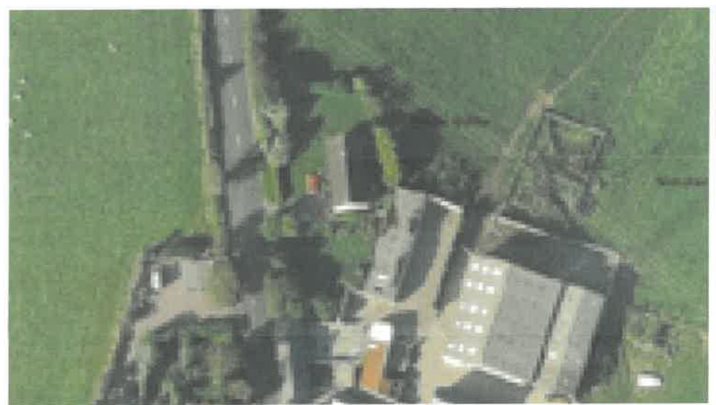 Aerial view of a rural property showing buildings, access roads, and surrounding green fields.