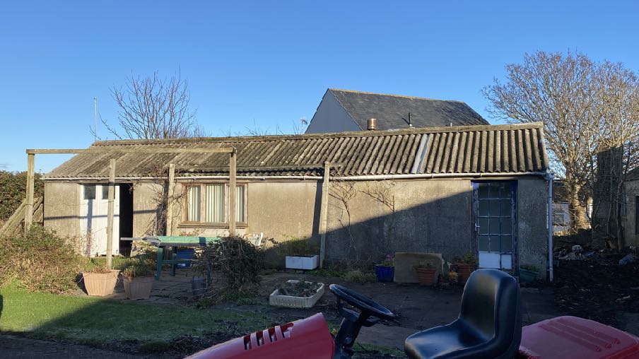 A photograph showing an existing single-storey building with a corrugated roof and a wooden pergola structure, likely the property subject to the planning application.