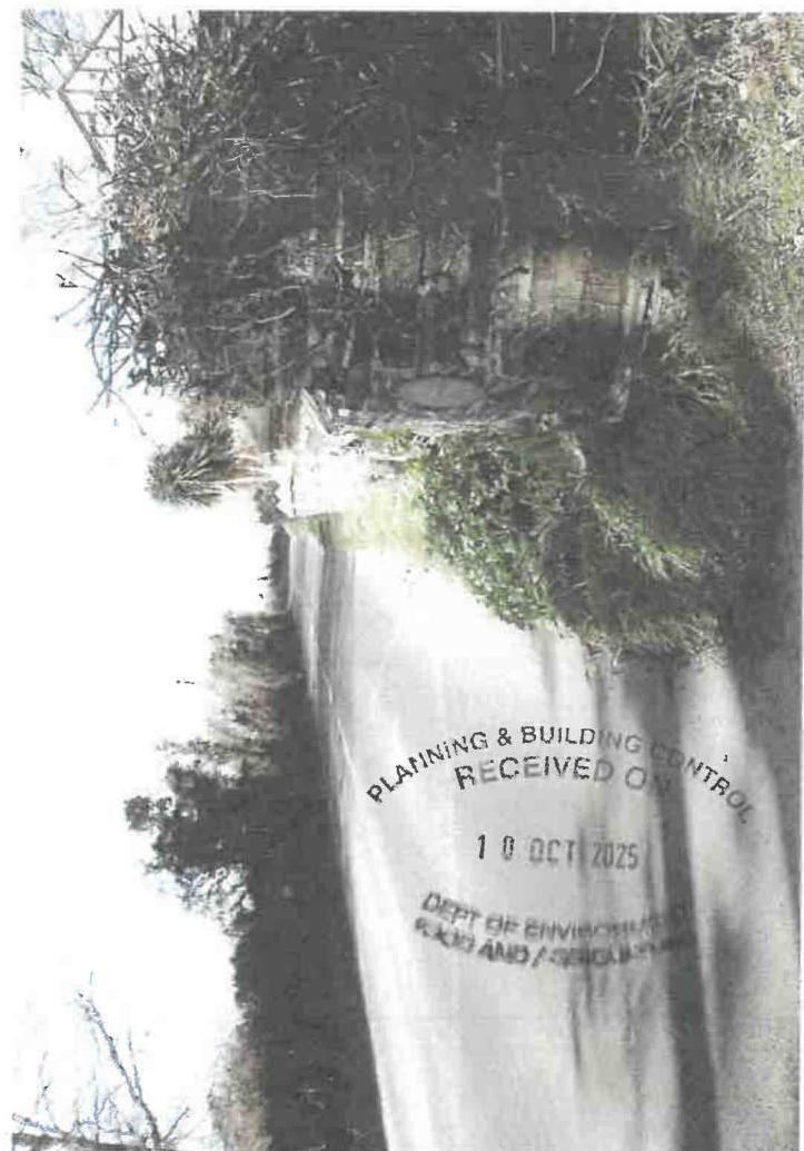 A rotated photograph showing a paved road or driveway bordered by dense vegetation, with a 'Planning & Building Control' received stamp overlaid on the image.