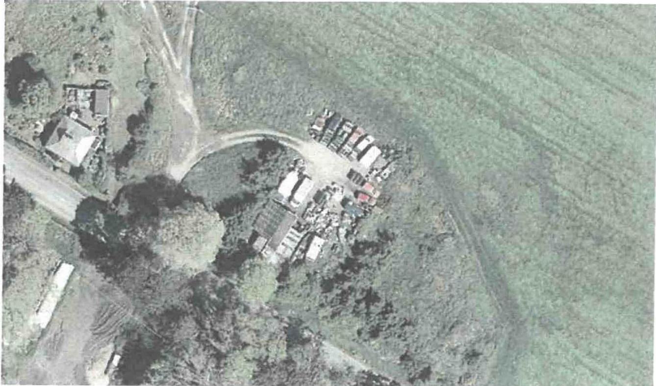 An aerial photograph showing a cluster of outbuildings and storage units situated in a rural field with access tracks.