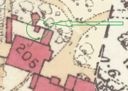 A cropped section of a topographical map showing red building footprints, with green digital annotations highlighting a specific structure and boundary line.