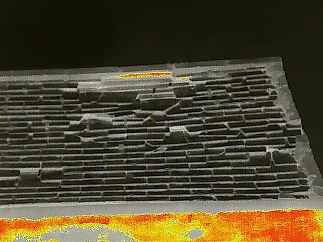 A close-up thermal image or digital scan of a slate roof structure, showing a grid pattern and a heat map overlay at the bottom.