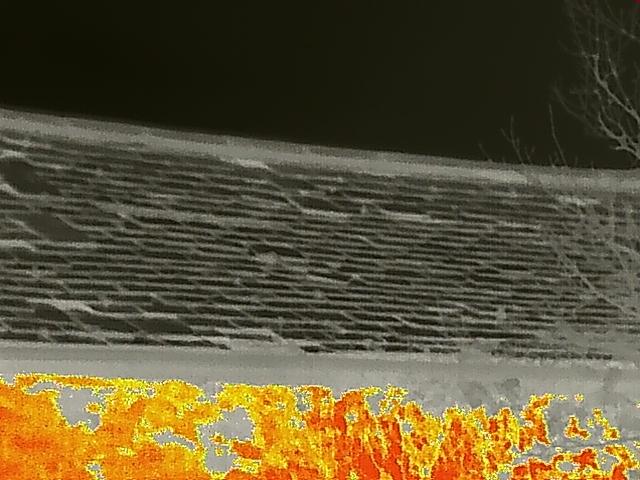 A close-up thermal or infrared image showing a tiled roof surface with a bright orange heat signature overlay at the bottom.