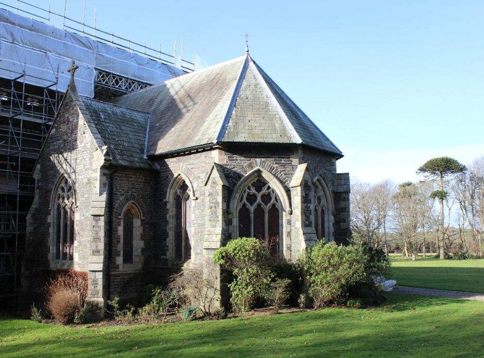 Exterior photograph of a stone chapel with Gothic windows, showing scaffolding and white sheeting indicating restoration work.