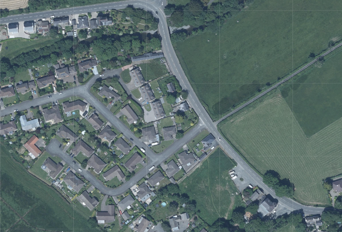 Aerial site location map showing a residential housing estate adjacent to open green fields and a main road.