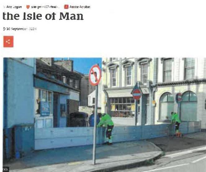 A street-level photograph showing a row of commercial buildings with blue construction hoarding being installed in the foreground by workers.