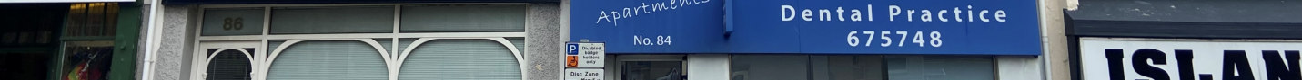 Street-level photograph of a commercial building facade featuring a dental practice and apartments with shopfront fenestration.