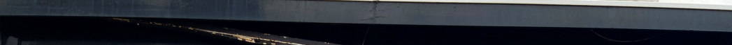A close-up, horizontal photograph showing the underside of a building's fascia board or roof overhang against a dark background.
