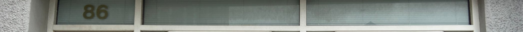 Close-up photograph of a building facade showing a window with the number 86, likely part of a shopfront.
