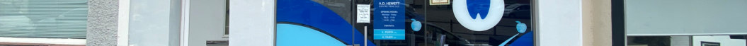 A street-level photograph showing the existing commercial shop frontage with blue window graphics and signage for A.D. Vernon.