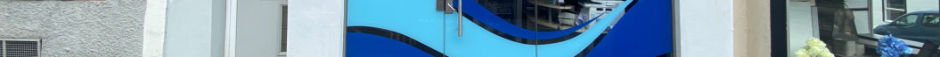 A close-up photograph of a commercial shopfront featuring blue wave-patterned glass panels and metal door handles.