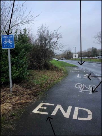A photograph showing a paved cycle path with a blue 'End of Route' sign and large white 'END' text painted on the ground.