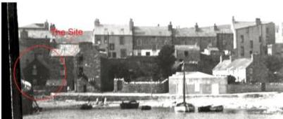 A black and white photograph showing a row of terraced buildings along a waterfront, with a specific building circled in red and labeled 'The Site'.